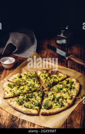 Tranches de pizza italienne avec brocoli, sauce pesto, épices et fromage sur du papier sulfurisé Banque D'Images