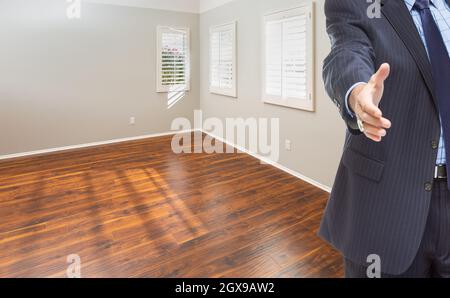 L'agent immobilier atteint pour la poignée de main à l'intérieur de la pièce vide de la nouvelle maison. Banque D'Images