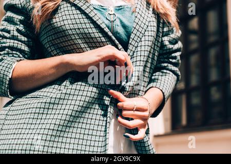 belles mains de femme avec manucure bleue et élément de manteau à carreaux élégant Banque D'Images
