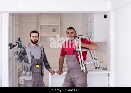 portrait de deux travailleurs professionnels lors de l'installation d'un nouveau mobilier moderne et élégant de cuisine Banque D'Images