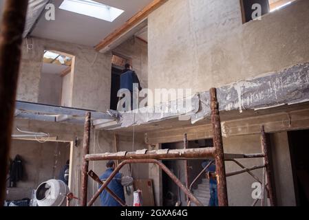 travailleurs sur le chantier intérieur de nouvel appartement de deux niveaux avec fenêtres et murs de briques rouges chantier en cours de construction à la nouvelle maison Banque D'Images