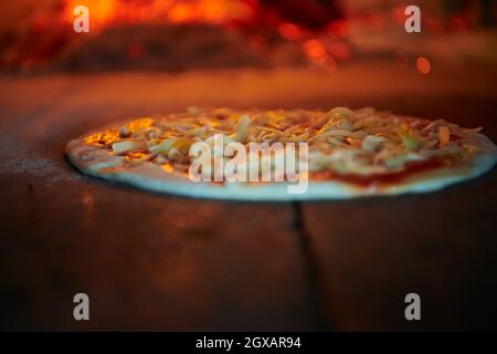 La pizza rustique est retirée de la cuisinière chaude où elle a été cuite. Faire cuire à l'aide d'une pelle spéciale pour les retirer. Ce restaurant dispose d'un four à bois spécial Banque D'Images