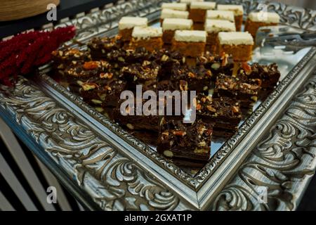 Tranches de biscuit aux noix, au cacao et au caramel à la table du buffet, servies sur le plateau argenté Banque D'Images