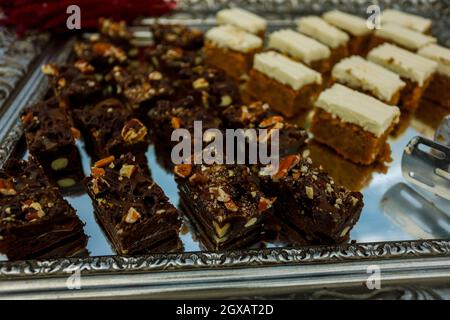 Tranches de biscuit aux noix, au cacao et au caramel à la table du buffet, servies sur le plateau argenté Banque D'Images