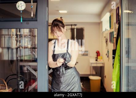 Portrait d'animal professionnel coiffure Femme hippie avec des tatouages tout en se tenant à la porte de son salon de beauté pour les animaux Banque D'Images