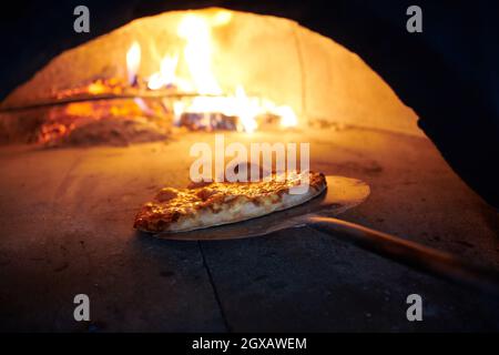 La pizza rustique est retirée de la cuisinière chaude où elle a été cuite. Faire cuire à l'aide d'une pelle spéciale pour les retirer. Ce restaurant dispose d'un four à bois spécial Banque D'Images