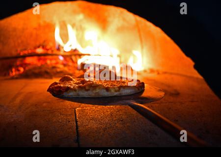 La pizza rustique est retirée de la cuisinière chaude où elle a été cuite. Faire cuire à l'aide d'une pelle spéciale pour les retirer. Ce restaurant dispose d'un four à bois spécial Banque D'Images