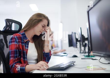 Femme d'affaires décontractée fatiguée prenant une pause tout en travaillant sur un ordinateur de bureau dans le plan ouvert moderne démarrage de bureau intérieur Date limite stress concept Banque D'Images