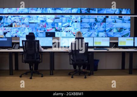 Groupe d'opérateurs de centre de données de sécurité travaillant dans une salle de surveillance CCTV regardant sur plusieurs moniteurs officiers surveillant plusieurs écrans pour Suspi Banque D'Images