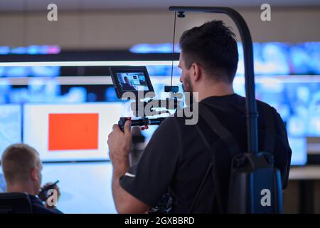 Vidéaste professionnel avec vidéo slr de gimball enregistrant la vidéo des opérateurs de centre de données de sécurité tout en travaillant dans une salle de surveillance de CCTV regardant Banque D'Images