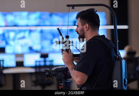 Vidéaste professionnel avec vidéo slr de gimball enregistrant la vidéo des opérateurs de centre de données de sécurité tout en travaillant dans une salle de surveillance de CCTV regardant Banque D'Images