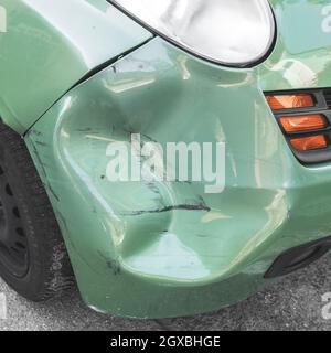 Voiture verte bosselée. La carrosserie latérale de la voiture a été endommagée par un accident dans la circulation. Gros plan. Banque D'Images