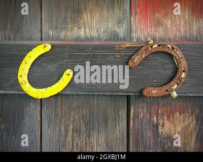 Deux fers à cheval rouillés suspendus sur une porte en bois Banque D'Images