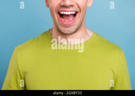 Photo de doux impressionné jeune homme porter un t-shirt vert souriant bouche ouverte isolé couleur bleue fond. Banque D'Images