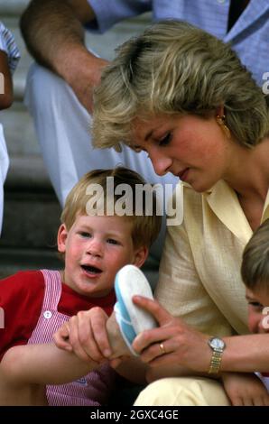 La princesse Diana, princesse de Galles aide le prince Harry à mettre ses chaussures en vacances à Majorque, Espagne, le 10 août 1987.Étaient également présents la famille royale espagnole et le Prince Charles, prince de Galles. Banque D'Images