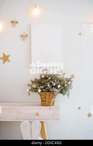 Composition de branches d'arbre de Noël avec jouets sur elles dans un panier en osier dans le décor de la chambre d'enfants Banque D'Images