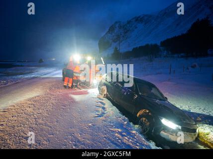 Voiture remorquée après un accident dans une tempête de neige sur une route glacée scandinave pendant la nuit froide d'hiver Banque D'Images