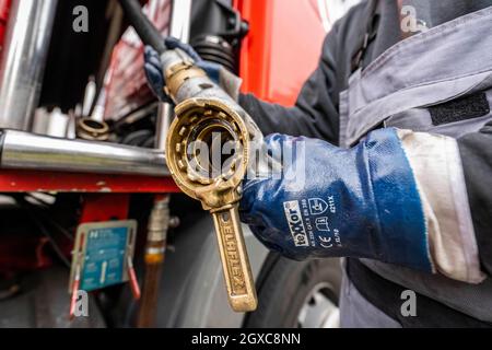 Lippstadt, Allemagne. 05e octobre 2021. Un employé tire le flexible d'alimentation en huile de chauffage vers un client hors du camion-citerne. Les consommateurs peuvent s’attendre à une forte hausse des coûts de chauffage cette année en raison de la forte demande mondiale de pétrole brut. Il sera encore plus cher en 2021 dans les maisons avec chauffage au pétrole, où les coûts devraient augmenter de 44 pour cent - après avoir chuté de 27 pour cent l'année précédente. Credit: David Inderlied/dpa/Alay Live News Banque D'Images