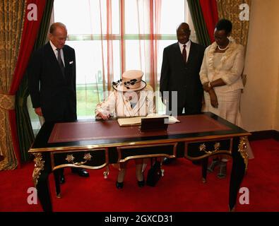 La reine Elizabeth II signe le livre des visiteurs observé par le prince Philip, duc d'Édimbourg, le président Yoweri Museveni et l'épouse Janet à la maison d'État d'Entebbe, en Ouganda.La Reine ouvrira vendredi la réunion des chefs de gouvernement du Commonwealth.Plus de 5000 délégués, le prince de Galles et la duchesse de Cornouailles, ainsi que le premier ministre britannique Gordon Brown, participeront au CHOGM. Banque D'Images