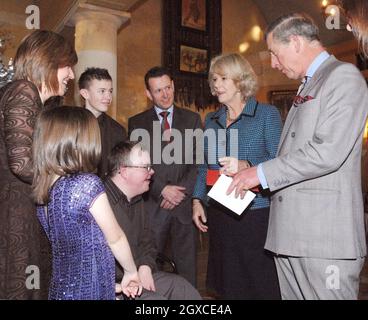 Le prince Charles, prince de Galles et Camilla, duchesse de Cornwall, reçoivent une carte de Greg Fears (centre assis), 16 ans, lorsqu'ils organisent une réception pour le personnel et les jeunes de l'hôpital pour enfants Ty Hafan à la maison Highgrove de Tetbury le 20 décembre 2007. Banque D'Images