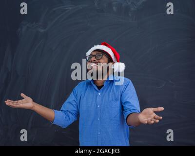 L'homme indien traditionnel port Santa Claus hat on chalkboard background studio la peau sombre Noël le nouvel an Banque D'Images