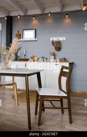 Une chaise en bois située à côté d''une table à plateau blanc dans la cuisine de style scandinave Banque D'Images