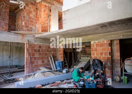 travailleurs sur le chantier intérieur de nouvel appartement de deux niveaux avec fenêtres et murs de briques rouges chantier en cours de construction à la nouvelle maison Banque D'Images