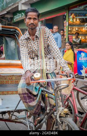 INDE, BANGLADESH - 6 DÉCEMBRE 2015 : homme ethnique assis en tricycle dans la rue de la ville Banque D'Images