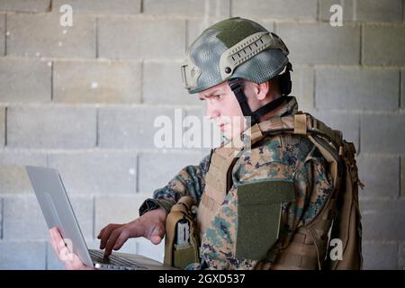 Soldat américain en uniforme militaire utilisant un ordinateur portable pour drone contrôler et rester en contact avec les amis et la famille Banque D'Images