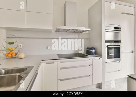 Design créatif de la cuisine avec cuisinière électrique et placard au-dessus des fruits frais dans la maison légère Banque D'Images