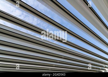 Faible angle de plafond de la maison moderne avec des panneaux en métal et des détails en verre sous le ciel bleu clair le jour ensoleillé Banque D'Images