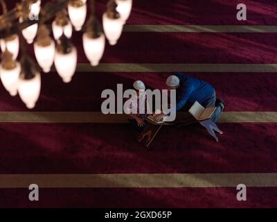 prière musulmane, père et fils dans la mosquée, priant et lisant le livre holly quran together islamique education concept Banque D'Images