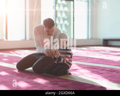 prière musulmane, père et fils dans la mosquée, priant et lisant le livre holly quran together islamique education concept Banque D'Images