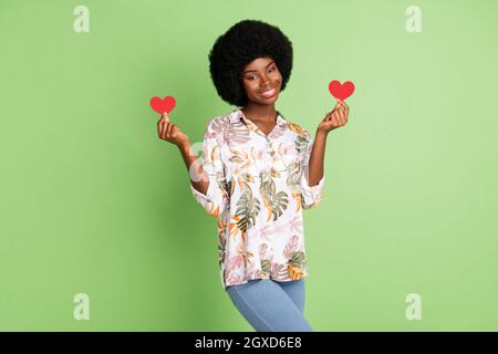Photo de jeune fille afro heureux sourire positif tenir petit papier coeur sentiments date romantique isolé sur fond vert couleur Banque D'Images