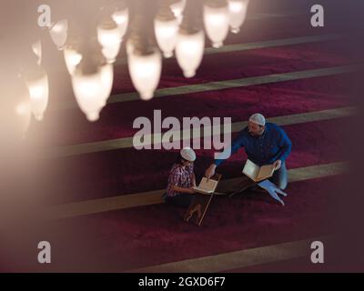 prière musulmane, père et fils dans la mosquée, priant et lisant le livre holly quran together islamique education concept Banque D'Images