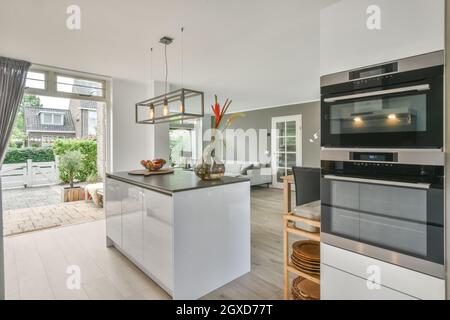 Arceaux avec fruits et légumes frais et vase avec fleurs placés sur une table dans la cuisine élégante de l'appartement contemporain Banque D'Images