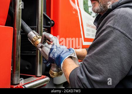 Lippstadt, Allemagne. 05e octobre 2021. Un employé tire le flexible d'alimentation en huile de chauffage vers un client hors du camion-citerne. Les consommateurs peuvent s’attendre à une forte hausse des coûts de chauffage cette année en raison de la forte demande mondiale de pétrole brut. Il sera encore plus cher en 2021 dans les maisons avec chauffage au pétrole, où les coûts devraient augmenter de 44 pour cent - après avoir chuté de 27 pour cent l'année précédente. Credit: David Inderlied/dpa/Alay Live News Banque D'Images