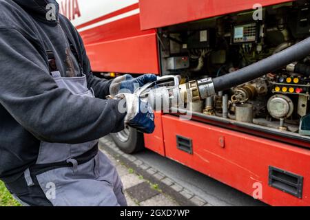 Lippstadt, Allemagne. 05e octobre 2021. Un employé tire le flexible d'alimentation en huile de chauffage vers un client hors du camion-citerne. Les consommateurs peuvent s’attendre à une forte hausse des coûts de chauffage cette année en raison de la forte demande mondiale de pétrole brut. Il sera encore plus cher en 2021 dans les maisons avec chauffage au pétrole, où les coûts devraient augmenter de 44 pour cent - après avoir chuté de 27 pour cent l'année précédente. Credit: David Inderlied/dpa/Alay Live News Banque D'Images