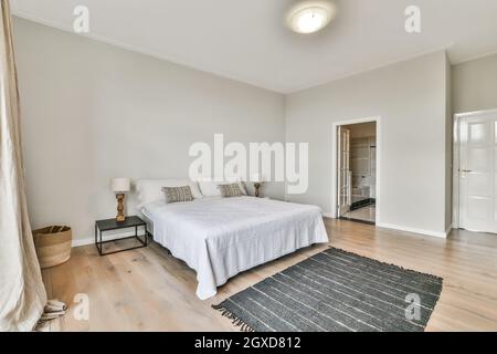 Chambre spacieuse et moderne avec salle de bain, lit confortable, table de chevet près de la moquette et salle de bain Banque D'Images