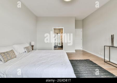 Chambre spacieuse et moderne avec salle de bain, lit confortable, table de chevet près de la moquette et salle de bain Banque D'Images