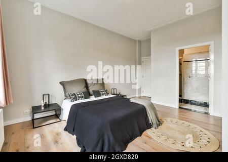 Chambre spacieuse et moderne avec salle de bain, lit confortable, table de chevet près de la moquette et salle de bain Banque D'Images