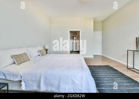 Chambre spacieuse et moderne avec salle de bain, lit confortable, table de chevet près de la moquette et salle de bain Banque D'Images