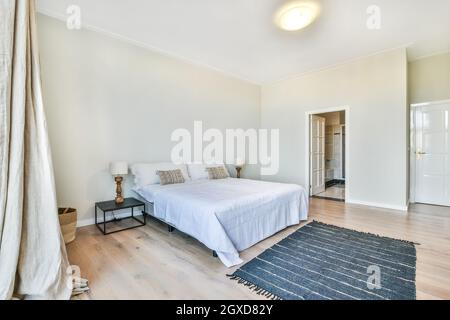 Chambre spacieuse et moderne avec salle de bain, lit confortable, table de chevet près de la moquette et salle de bain Banque D'Images