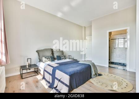 Chambre spacieuse et moderne avec salle de bain, lit confortable, table de chevet près de la moquette et salle de bain Banque D'Images