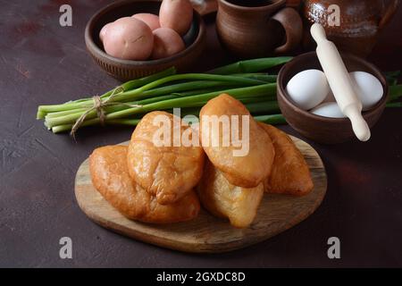 Viandes russes (Pasties, Hot cakes, Pirozhki, tartes) sur placard en bois. Tartes frites maison traditionnelles avec pommes de terre Banque D'Images