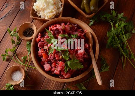 Vinegret ou vinaigrette. Salade rouge russe traditionnelle avec légumes cuits et marinés, petits pois, betteraves, dans un bol en bois sur fond rustique. Banque D'Images