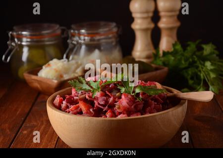 Vinegret ou vinaigrette. Salade rouge russe traditionnelle avec légumes cuits et marinés, petits pois, betteraves, dans un bol en bois sur fond rustique. Banque D'Images