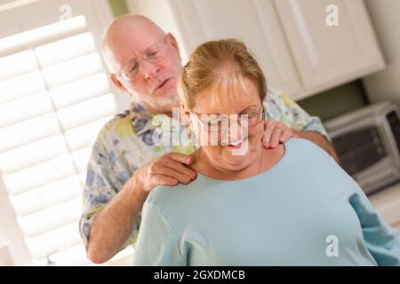 Happy Senior Adulte mari épouse donnant une épaule frotter dans la cuisine. Banque D'Images