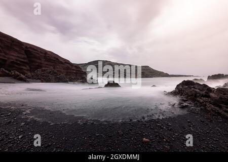 Ciclos Beach contre la mer brumeux et le volcan Guincho sous ciel nuageux à Golfo Yaiza Lanzarote îles Canaries Espagne Banque D'Images