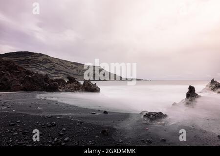 Ciclos Beach contre la mer brumeux et le volcan Guincho sous ciel nuageux à Golfo Yaiza Lanzarote îles Canaries Espagne Banque D'Images